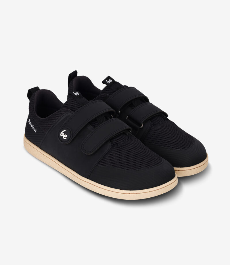 Sorte barfodssko med beige såler, to velcroremme, bred tåboks, minimalistisk stil, be-logo på siden.