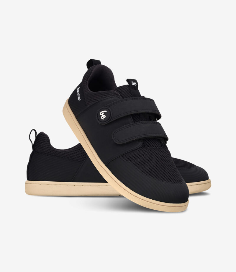 Sorte minimalistiske barfodssneakers med beige såler, overdel i mesh, bred tåboks og velcroremme til afslappet brug.