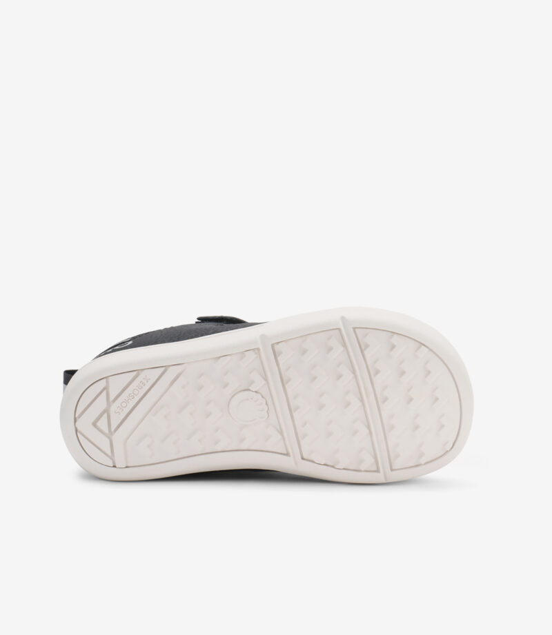 Nederste del af Xero Prio Mindre børn barfodssko i sort/hvid, minimalistisk design, struktureret hvid gummisål, bred tåboks.