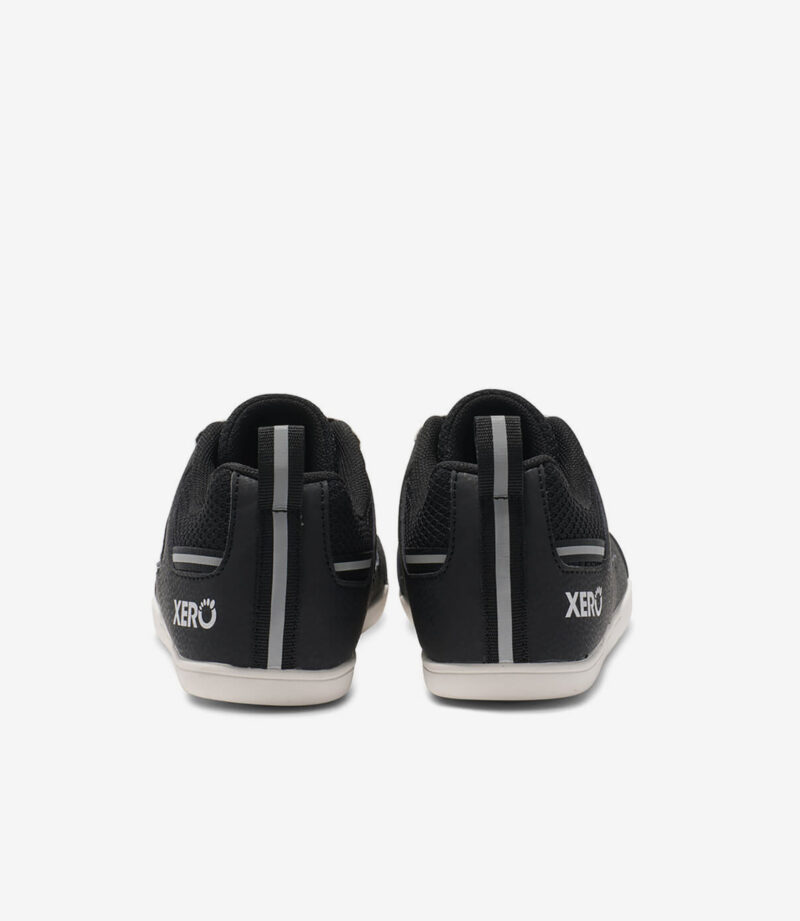 Sorte og hvide Xero Prio børn barfodssneakers, minimalistisk stil, bred tåboks, grå stribe og XERO-logo på hælen.