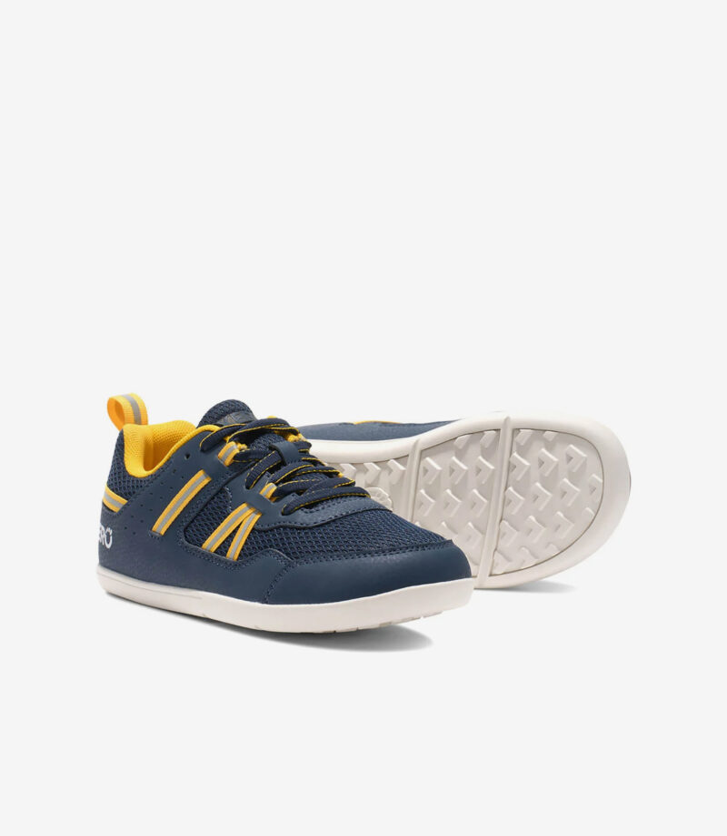 Xero Prio børn barfodssko i marineblå med gule detaljer, hvide såler, bred tåboks, minimalistisk sneaker-stil.
