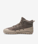 Taupe og beige Xero Scrambler Trail Mid barfodsvandrestøvle med bred tåboks, robust sål og forstærket tå på hvid baggrund.