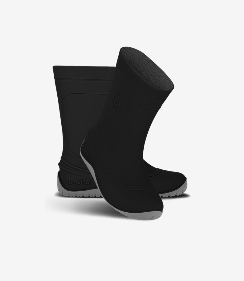 Sorte, minimalistiske barfodsgummistøvler med bred tå, grå såler med struktur, stående og vippende på en ren, hvid baggrund.